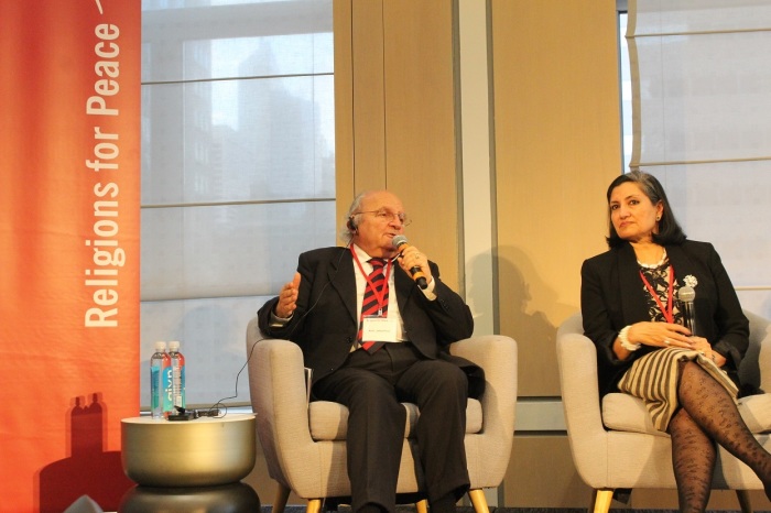 Jakob Finci, president of the Jewish Community of Bosnia and Herzegovina speaks at the Religions for Peace Conference in New York City on Wednesday December 11, 2019. Bani Dugal, principal representative to the United Nations, Bahá’í International Community and co-president of Religions for Peace, US, listens intently.