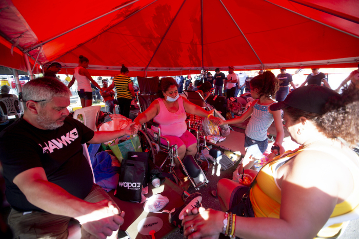 Wanda Santana (C in wheelchair) prays along members pf her familiay at the refugee camp located at the Mariano Rodríguez Coliseum on January 11, 2020 in Guanica, Puerto Rico. Saturday morning's quake was the most powerful aftershock following Tuesday's 6.4 earthquake.