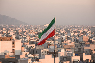 Iranian flag waving with cityscape on background in Tehran, Iran