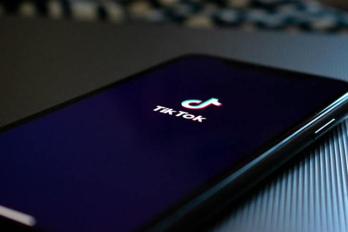 A phone screen displays the TikTok logo.