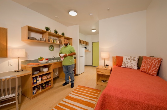 A resident of New Hope Housing Perry prepares to cook in his kitchen. Each room at NHH Perry features a refrigerator and microwave.