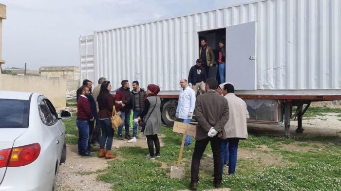 People stand outside of a 'hospitainer' mobile medical clinic in Syria.