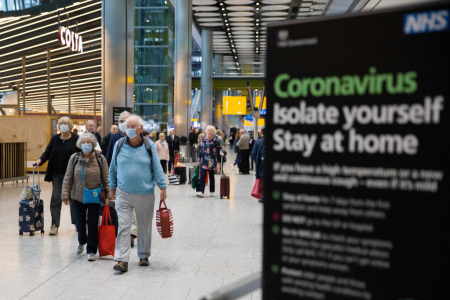 Travelers who had been aboard the Braemar cruise ship, operated by Fred Olsen Cruise Lines, and wearing face masks as a precautionary measure against covid-19, react as they arrive at Heathrow Airport in London on March 19, 2020.