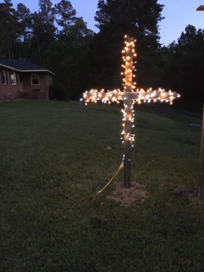 A cross lit with Christmas lights is placed in front of a house in Kentucky.