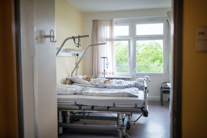 A patient lies on a bed in a hospital room.