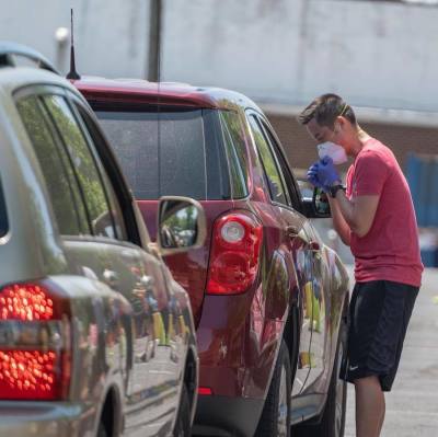 A volunteer at McLean Bible Church prays with a visitor during a food distribution event for families in need, May 2020.