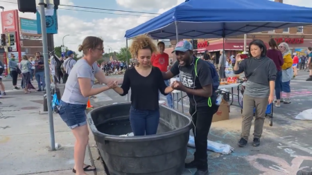 A woman gets baptized near the Cup Foods store where George Floyd was killed in Minneapolis, Minn.