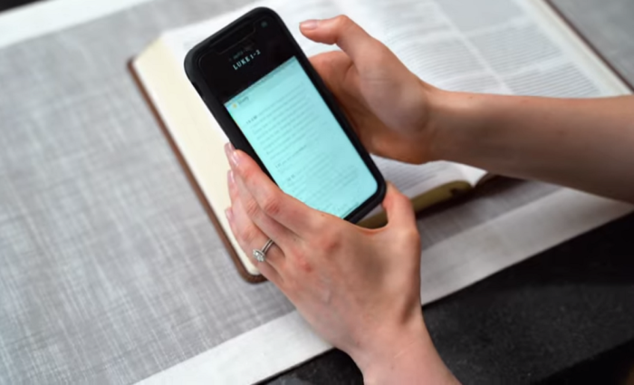 A woman looks at the Filament mobile app while reading a Filament Bible published by Tyndale House Publishers.