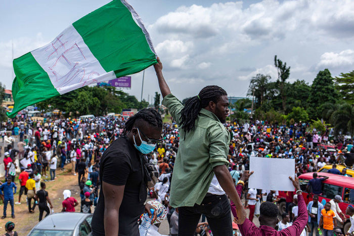 A Nigerian youth seen waving the Nigerian national flag in support of the ongoing protest against the unjust brutality of The Nigerian Police Force Unit named Special Anti-Robbery Squad (SARS) in Lagos on October 13, 2020. - Nigerians took to the streets once again on October 13, 2020, in several cities for fresh protests against police brutality, bringing key roads to a standstill in economic hub Lagos. Demonstrations organised on social media erupted earlier this month calling for the abolition of a notorious police unit accused of unlawful arrests, torture and extra-judicial killings. The government gave in to the demand on October 11, 2020, announcing that the federal Special Anti-Robbery Squad (SARS) was being disbanded in a rare concession to people power in Africa's most populous nation. 