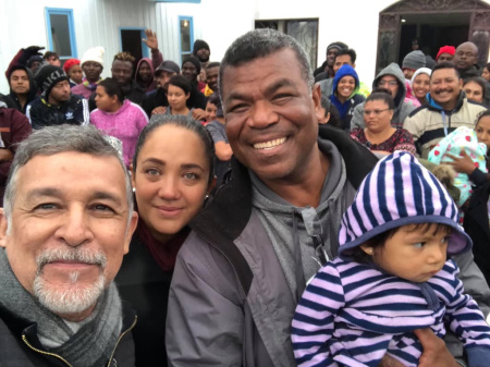 Pastor Hector Silva (holding child) poses with people at Senda de Vida Casa del Emigrante