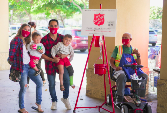 Carlos and Alexa PenaVega pose next to a Salvation Army red kettle, 2020.