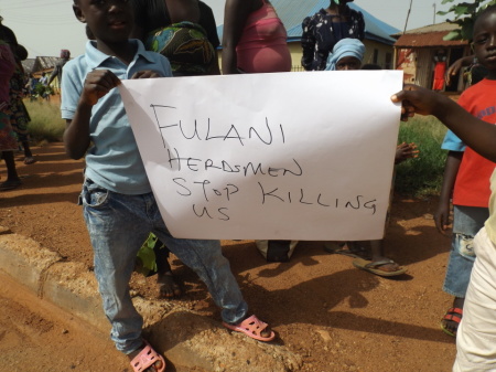 Nigerians hold a sign urging for an end to killings.