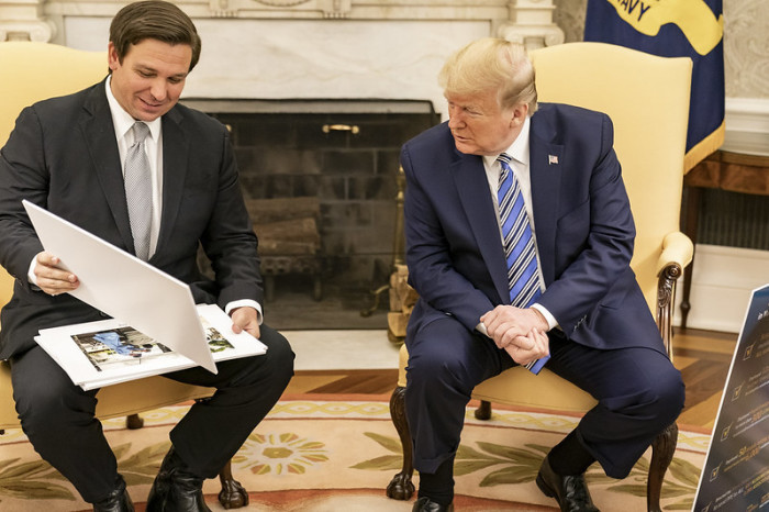 President Donald J. Trump looks at diagrams and photos during his meeting with Florida Gov. Ron DeSantis Tuesday, April 28, 2020, in the Oval Office of the White House. 