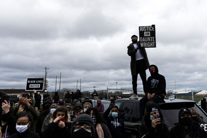 People gather holding signs and flags before curfew to protest the death of Daunte Wright, who was shot and killed by a police officer in Brooklyn Center, Minnesota on April 12, 2021.