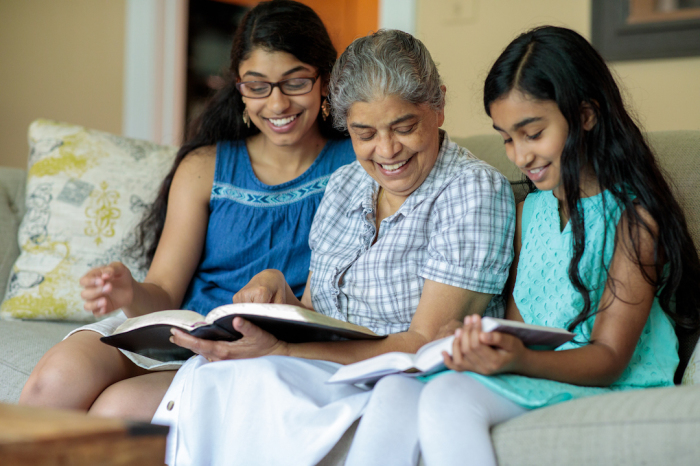 A woman and two young girls study the Bible. 