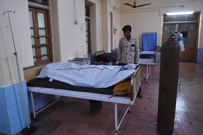 A family member mourns next to the body of a COVID-19 coronavirus victim in a hospital in Mahua on May 18, 2021, after Cyclone Tauktae hit the west coast of India with powerful winds and driving rain, leaving at least 20 people dead. 