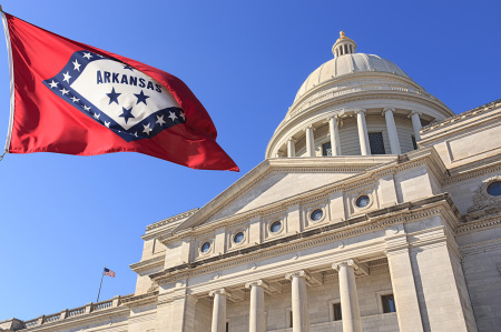 Arkansas flag flying high beside the Arkansas state Capitol, front exterior, in Little Rock, Arkansas.