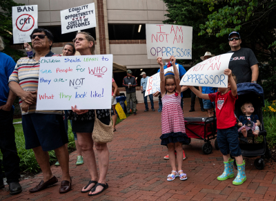 People hold up signs during a rally against 'critical race theory' (CRT) being taught in schools at the Loudoun County Government center in Leesburg, Virginia on June 12, 2021. 