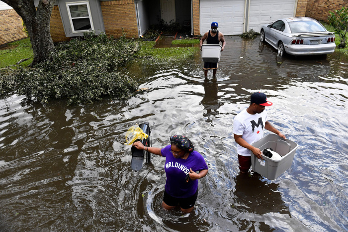 Darrin Heisser (C) evacuates from his flooded home with his dog Sonny and the help of daughter Darion Heisser (L) and Troy Gerard (R) as they wade into a high water truck volunteering to evacuate people from flooded homes in LaPlace, Louisiana on August 30, 2021 in the aftermath of Hurricane Ida. - Rescuers on Monday combed through the 'catastrophic' damage Hurricane Ida did to Louisiana, a day after the fierce storm killed at least two people, stranded others in rising floodwaters and sheared the roofs off homes. 