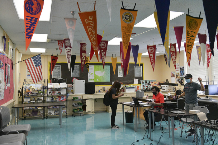 IT Support Technician Michael Hakopian (R) distributes computer devices to students at Hollywood High School on August 13, 2020, in Hollywood, California. With over 734,000 enrolled students, the Los Angeles Unified School District is the largest public school system in California and the 2nd largest public school district in the United States. 