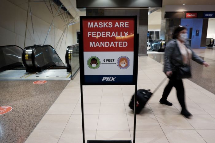 People walk through Sky Harbor International Airport in Phoenix, where new COVID-19 cases are down but health experts warn cases may rise with the introduction of the omicron strain on December 18, 2021. According to the Arizona Department of Health Services, since mid-December 2020, over 14,000 people have died of COVID-19 in Arizona. Arizona Governor Doug Ducey has signed an executive order banning local governments from imposing the vaccine requirements. Arizona does not yet have a mask mandate and mask use is sporadic.