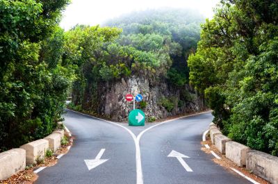 Two-lane road with each lane going in a different direction around a rock. Proper and dramatic arrow signaling.