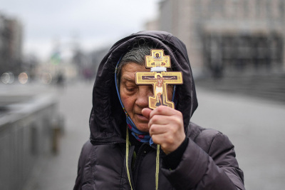 A religious woman holds a cross as she prays on Independence square in Kyiv in the morning of Feb. 24, 2022. 