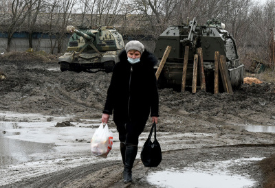 A woman walks in front of Russian armored vehicles parked at a railway station in the southern Russian Rostov region on February 25, 2022. 