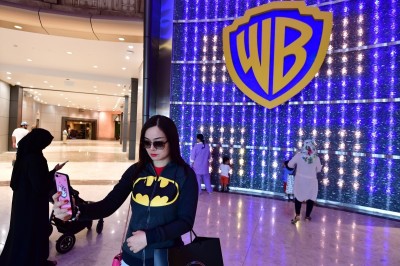 A woman takes a selfie with the logo at Warner Bros. World, the first-ever Warner branded indoor theme park, in the UAE capital Abu Dhabi on July 27, 2018. - The park officially opened to the public on July 25 after two years of construction. 