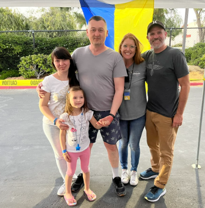 Calvary church members stand in front of the flag for Ukraine, next to Ukrainian refugees in Chula Vista, California. 