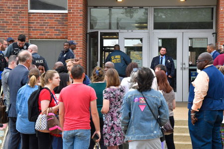 St. Louis metropolitan police and school officials stand outside the south entrance to the Central Visual and Performing Arts High School after a shooting that left three people dead including the shooter in St Louis, Missouri on Oct. 24, 2022. - Two people were killed on Monday and several were injured by a gunman who opened fire at a high school in the midwestern U.S. city of St. Louis, police said.