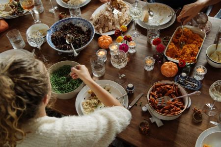 A girl eats while sitting at the dining table during Thanksgiving. 