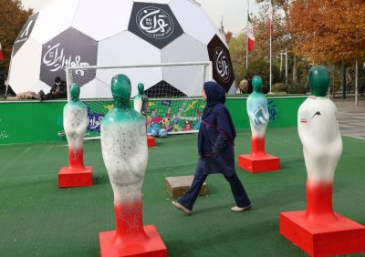 An Iranian woman walks at a football-themed outdoors fair set-up for the Qatar 2022 World Cup, in front of Mellat Park in the north of Tehran, on November 28, 2022.