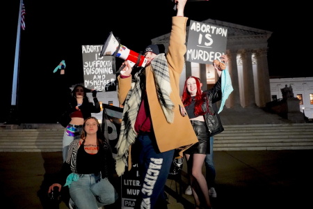 A pro-choice demonstrator walks by as pro-lifers rally on Dec. 1, 2022, at the U.S. Supreme Court Building in Washington, D.C.