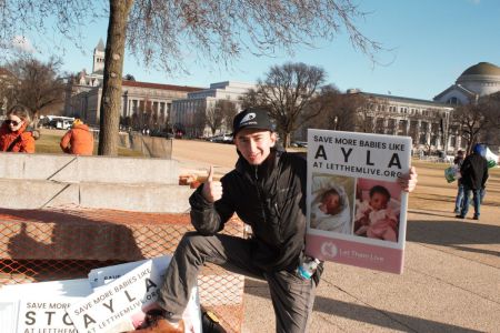 Maison Des Champs, a pro-life activist known as the 'Pro-Life Spiderman,' poses with signs at the March for Life in Washington, D.C., on Jan. 20, 2023.