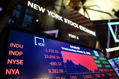 A screen shows the graph of the Dow industrial average after the closing bell at the New York Stock Exchange (NYSE) on March 18, 2020, at Wall Street in New York City. 