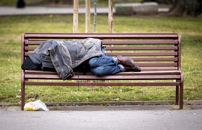 Homeless individual sleeping on a park bench.