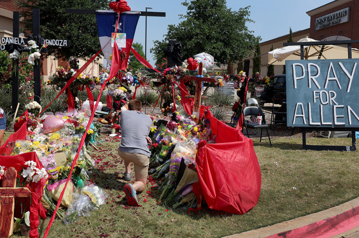 A person prays as they visit the memorial set up near the scene of a mass shooting at the Allen Premium Outlets mall on May 9, 2023, in Allen, Texas. Eight people were killed and seven wounded in the attack on May 6. The gunman was killed at the scene by an Allen Police officer responding to an unrelated call. 