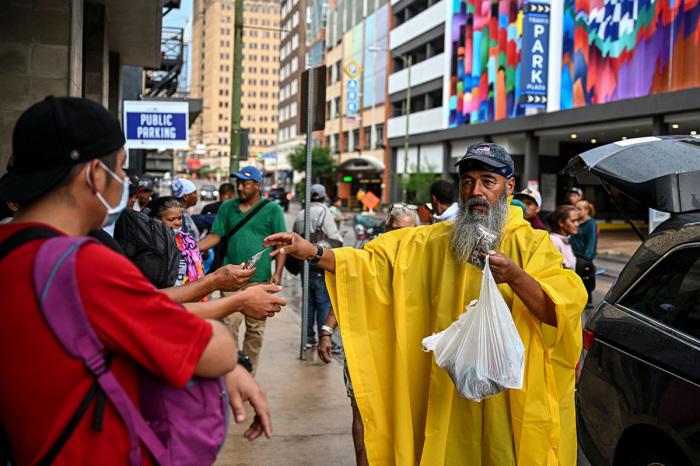 Reinaldo Calderon (R) distributes essentials to illegal immigrants as they wait outside a shelter home in San Antonio, Texas, on June 28, 2022. 