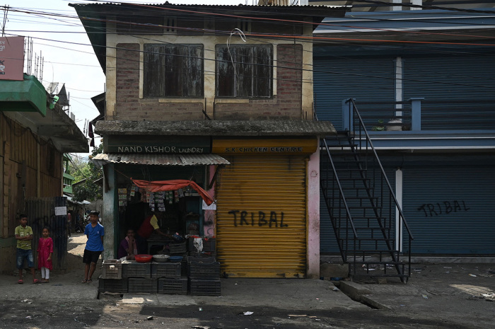 Local residents stand next to shops in Churachandpur as violence hit the northeastern Indian state of Manipur on May 9, 2023. More than 50 people have been killed in the hilly border region in clashes between the majority Meitei people, who are mostly Hindus, and the mainly Christian Kuki tribe. Thousands of troops have been deployed to restore order, while around 23,000 residents have fled their homes for the safety of ad-hoc army-run camps for the displaced. 