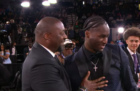 Atlanta Hawks forward, Adrian Griffin Jr., 19 (R), stands as he is selected as the 16th overall draft pick by the Atlanta Hawks in the 2022 NBA draft. His father, Milwaukee Bucks head coach Adrian Griffin Sr. (L) congratulates him.