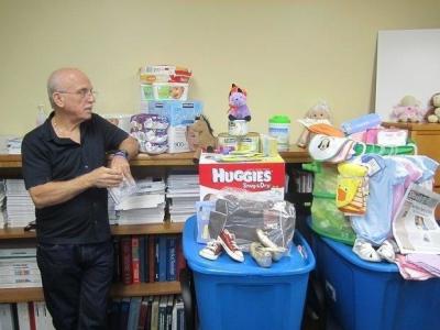 A Safe Haven for Newborns founder, Nick Silverio, stands next to multiple baby items. 