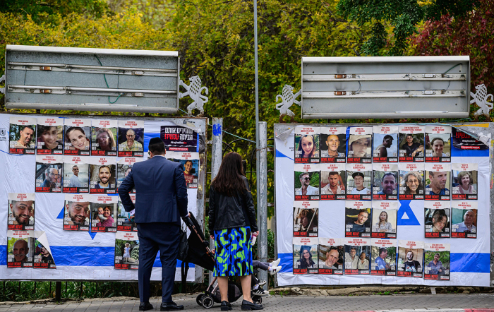 A couple with children looks at portraits of Israeli hostages held in Gaza since the October 7 attacks by Hamas terrorists, on billboards in Jerusalem.