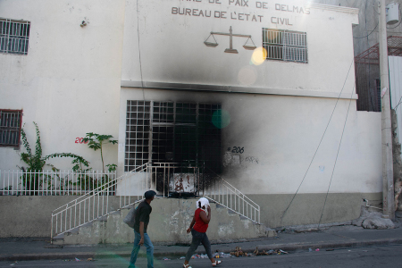 People walk by and look at the tribunal set on fire the previous day by armed gangs, in Port-au-Prince, Haiti, March 6, 2024. Haiti's capital was largely shut down March 4, 2024, with residents only venturing out for essentials, AFP reporters witnessed, as authorities imposed a state of emergency after an attack on a prison freed thousands of inmates. 