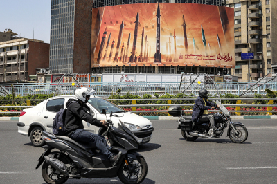 Motorists drive their vehicles past a billboard depicting named Iranian ballistic missiles in service, with text in Arabic reading 'the honest [person's] promise' and in Persian 'Israel is weaker than a spider's web,' in Valiasr Square in central Tehran on April 15, 2024. Iran on April 14 urged Israel not to retaliate militarily to an unprecedented attack overnight, which Tehran presented as a justified response to a deadly strike on its consulate building in Damascus. 