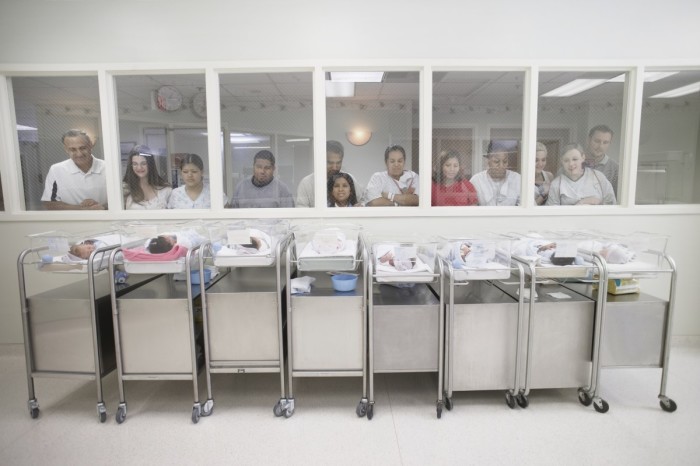 New parents watching babies in hospital nursery