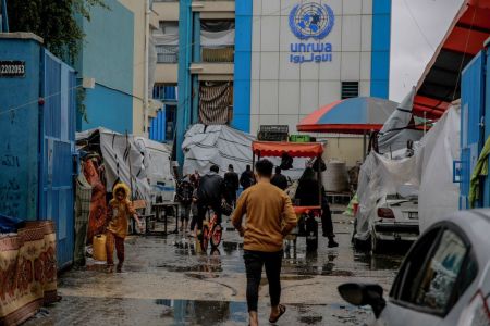 Palestinians walk at the entrance of a UNWRA school used as shelter in Gaza City on November 27, 2023. Omar El-Qattaa / AFP) (Photo by OMAR EL-QATTAA/AFP via Getty Images) 