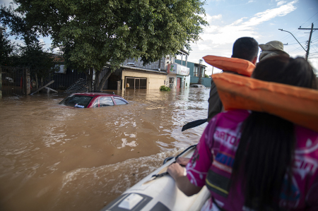 Katiane Mello (R) leaves her flooded home in a boat navigating a street in Eldorado do Sul, Rio Grande do Sul state, Brazil, on May 9, 2024. Teams raced against the clock Thursday to deliver aid to flood-stricken communities in southern Brazil before the arrival of new storms forecast to batter the region again. Some 400 municipalities have been affected by the worst natural calamity ever to hit the state of Rio Grande do Sul, with at least 136 people dead and hundreds injured.