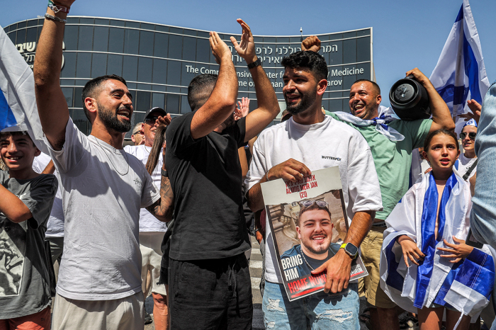 A man holds a picture of Almog Meir Jan, one of the four Israeli hostages who were rescued from captivity in the Gaza Strip since the October 7 attacks, outside Sheba Tel-HaShomer Medical Centre after they were transferred there, in Ramat Gan on June 8, 2024. The four had been kidnapped by Hamas from the Nova music festival during the October 7 attacks that sparked the war, the army said. 