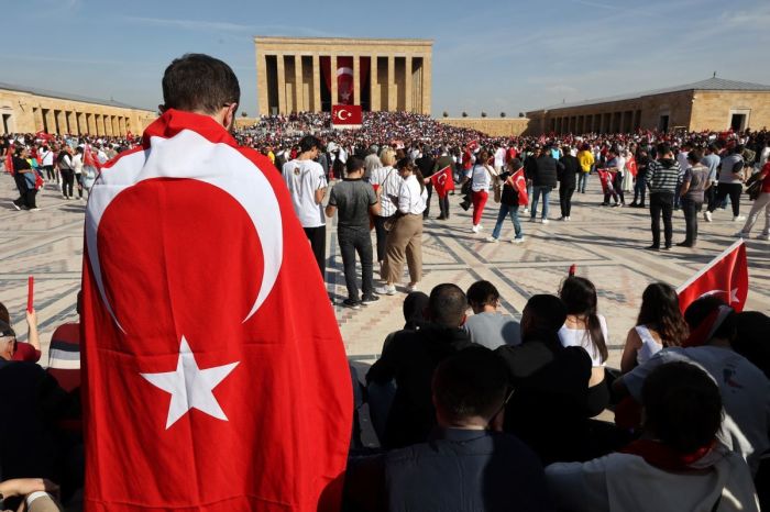 A man stands wrapped in the national flag of Turkey outside Anitkabir, the mausoleum of the Turkish Republic's Founder Mustafa Kemal Ataturk, as people gather to mark the 100th anniversary of the Republic of Turkey in Ankara, on October 29, 2023. 